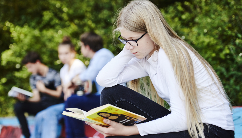 Billede af pige, der læser udendørs